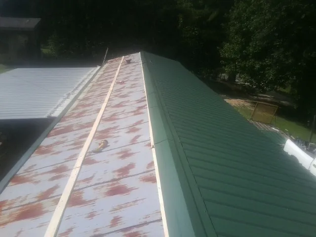 Old rusted panels beside newly installed green metal roofing — Wind Damage Roof Repair by Roofing Brothers in East Flat Rock