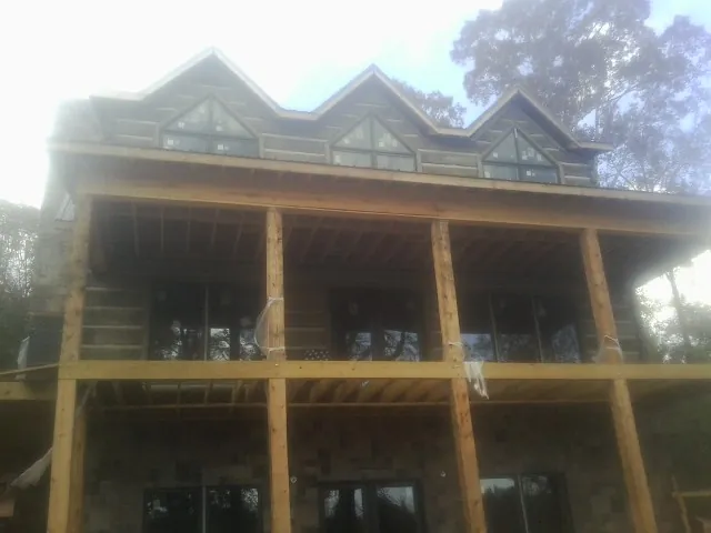 Dormers and porch framing on a large log home under construction — Roof Coating work by our crew in East Flat Rock