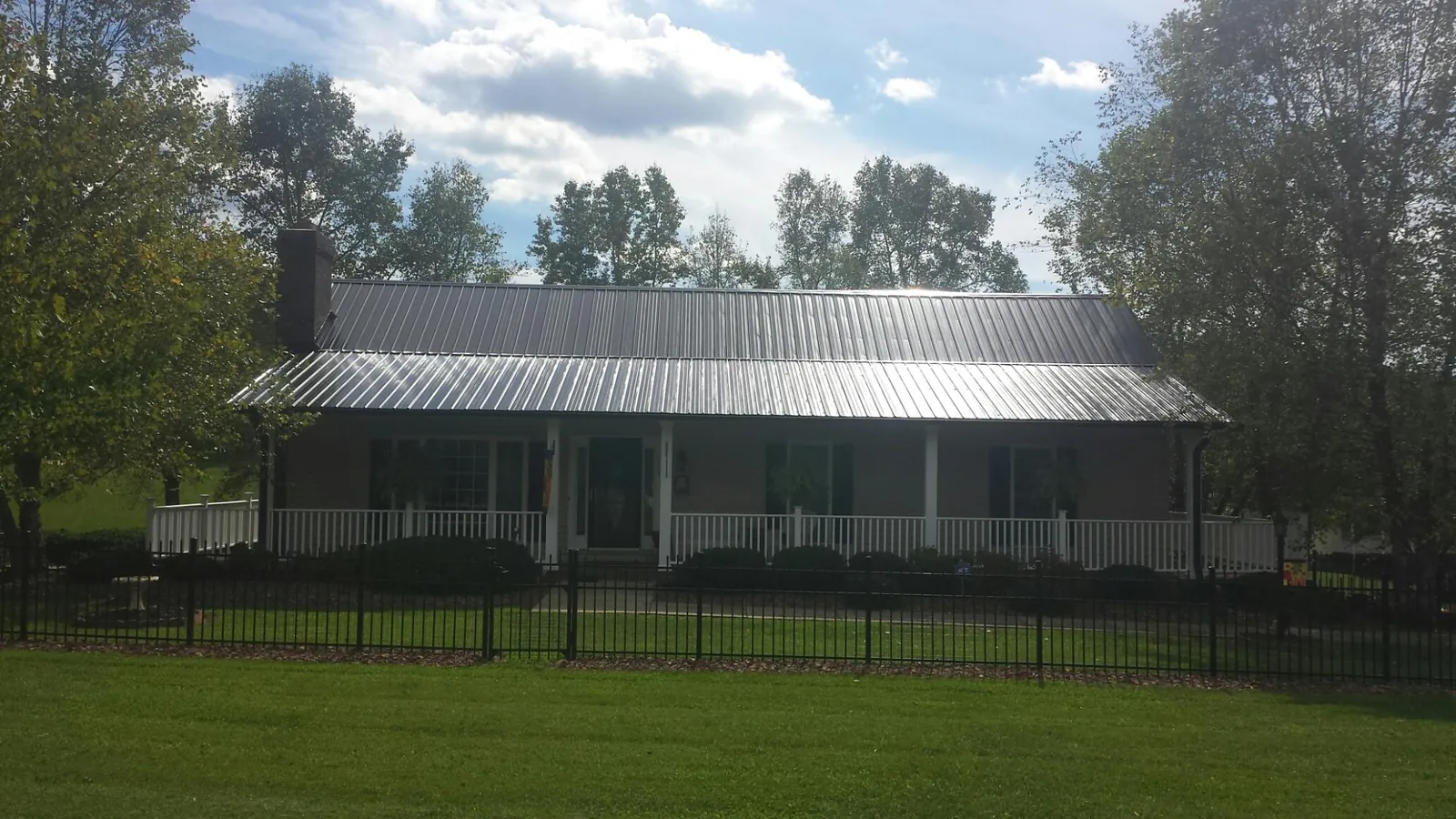 Gray metal roof on a brick ranch with a full width front porch — Gutter Guard Installation work by our crew in East Flat Rock