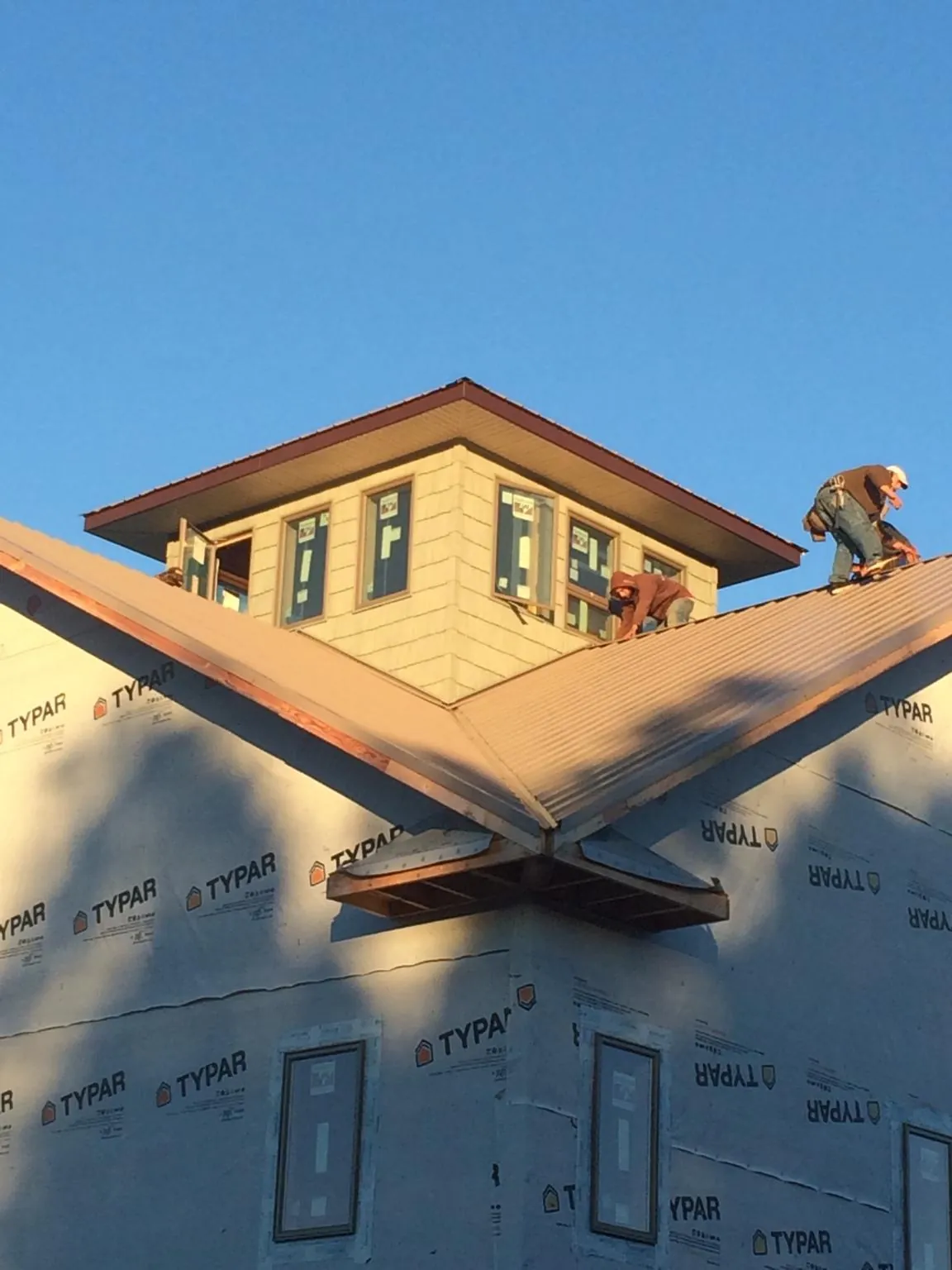 Roofers working around a rooftop cupola on a new metal roof at sunset — Roof Waterproofing in East Flat Rock by Roofing Brothers